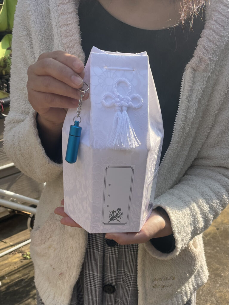 拾骨後の骨壷と遺骨キーホルダーを抱える飼い主様｜訪問ペット火葬