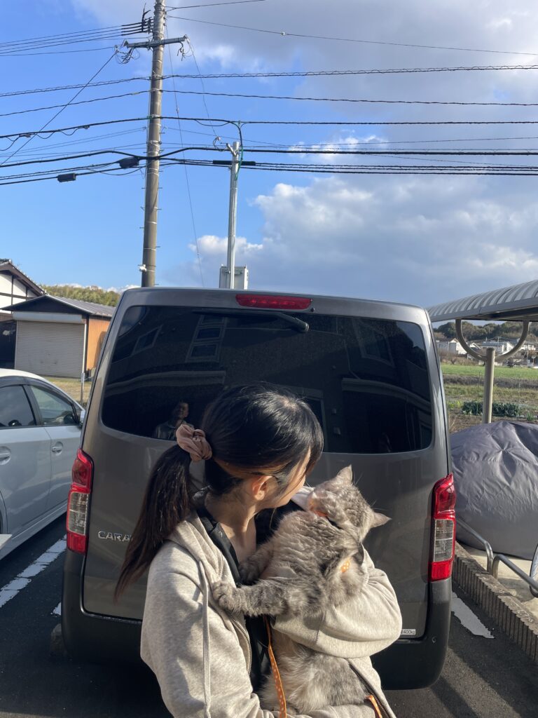 兄弟猫を抱きながら火葬車の前でまるちゃんを見送る家族